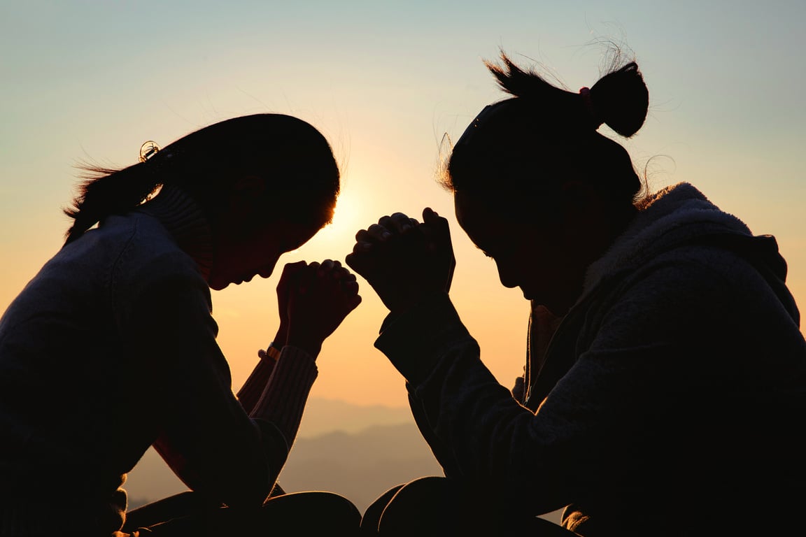 Silhouette of Two Women Praying Outdoors